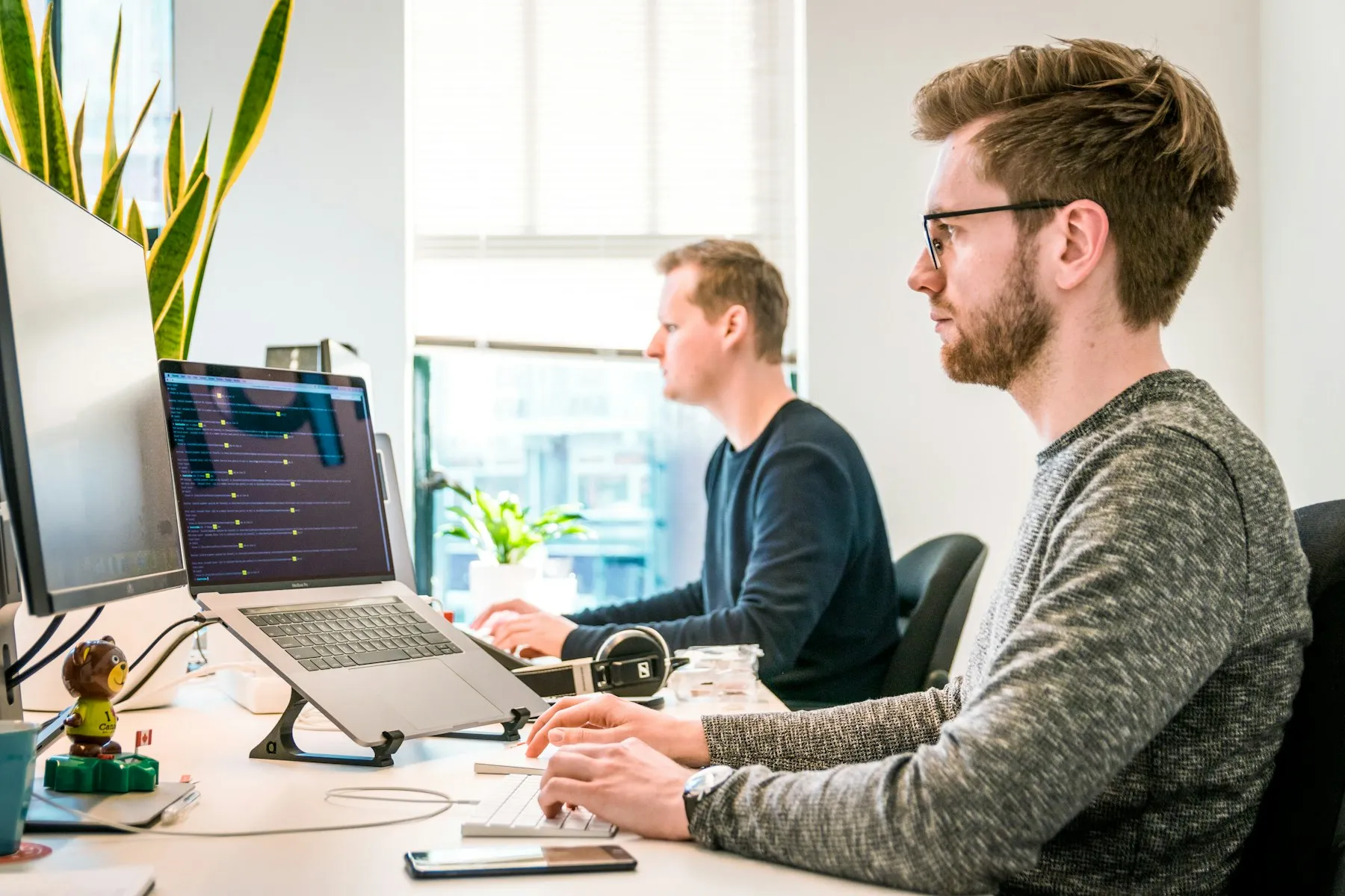 Two software engineers working at their monitors